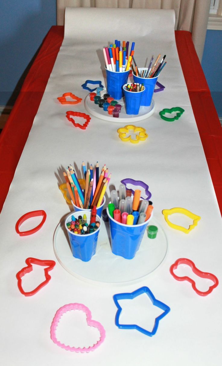 the table is set up with markers, pencils, and cups for art work