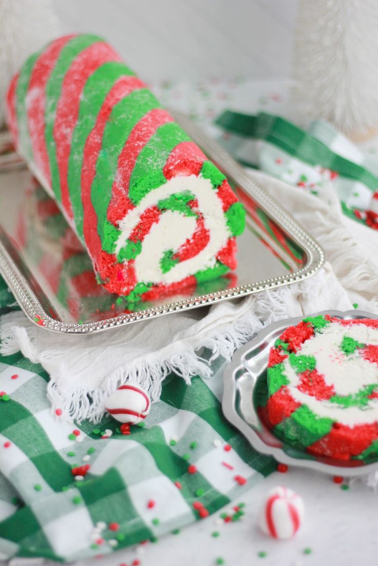 a cake roll decorated with green and red icing on a tray next to candy canes