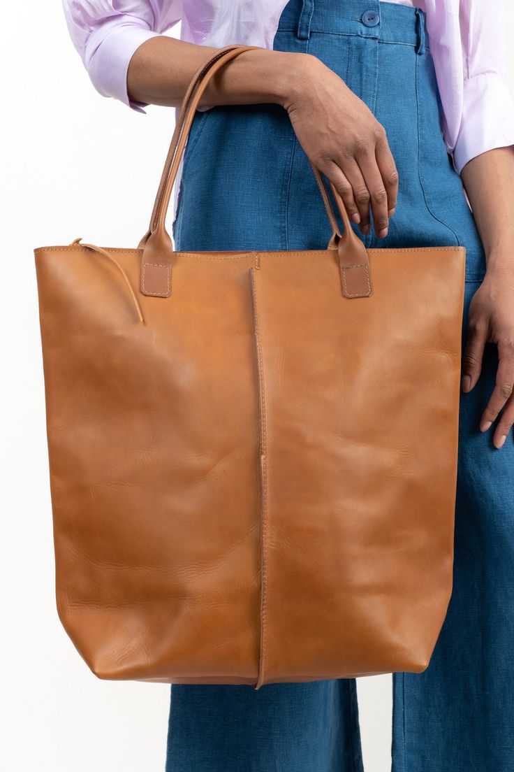 This large, durable leather tote is perfect for bringing along on trips to the farmers market, beach, or picnics. Crafted with high-quality 1.8mm vegetable-tanned Italian leather that is water-resistant and features a zippered shoulder bag design with a front-panel seam, key-hook, and spacious interior pocket. Travel Tote Bag With Vegetable-tanned Leather, Vegetable-tanned Leather Tote Satchel, Vegetable-tanned Leather Satchel Tote, Rectangular Vegetable-tanned Satchel For Travel, Vegetable Tanned Leather Travel Tote Shoulder Bag, Vegetable Tanned Leather Tote Shoulder Bag For Travel, Travel Bucket Bag With Smooth Grain, Vegetable-tanned Leather Tote Shoulder Bag, Travel Bucket Tote Bag