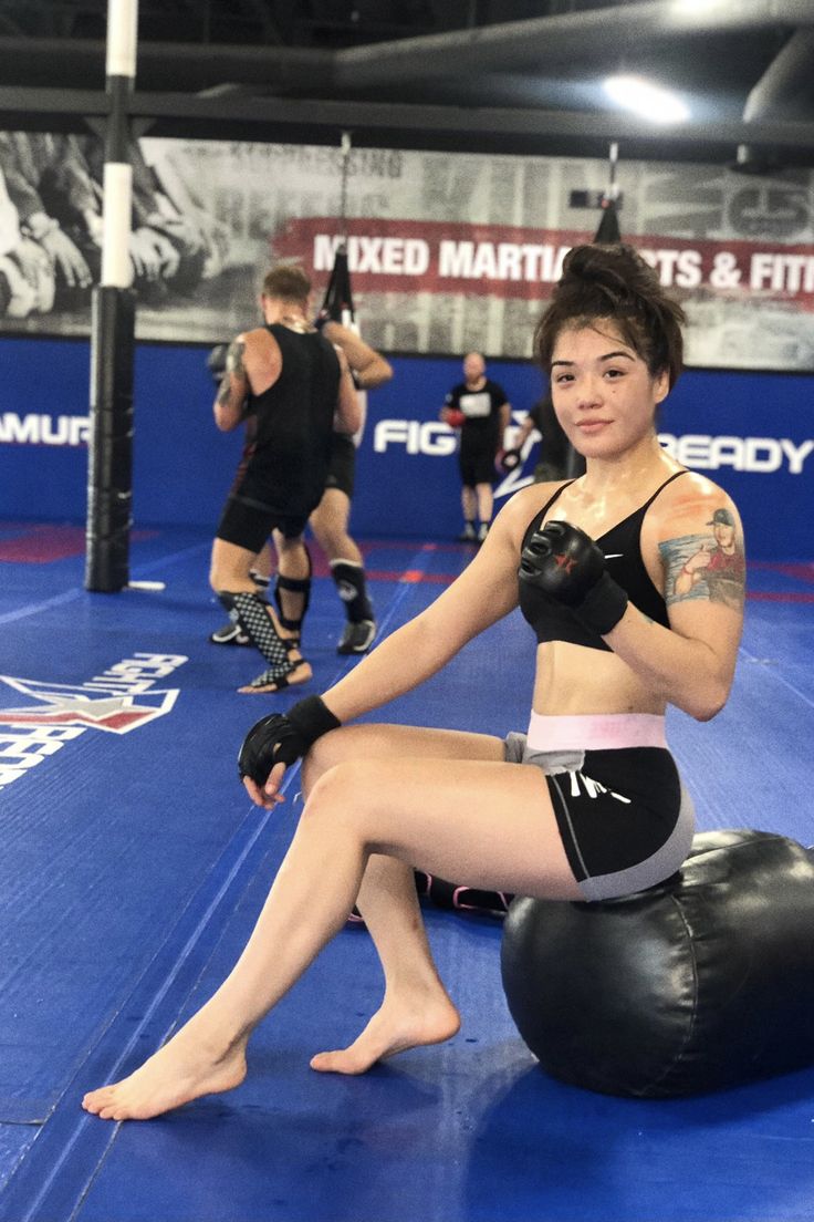 a woman sitting on top of a punching bag