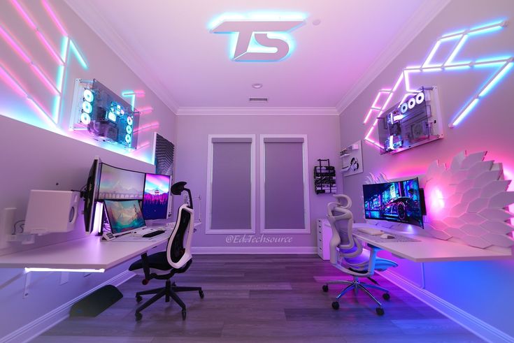 a room with two computers and neon lights on the walls, along with other desks