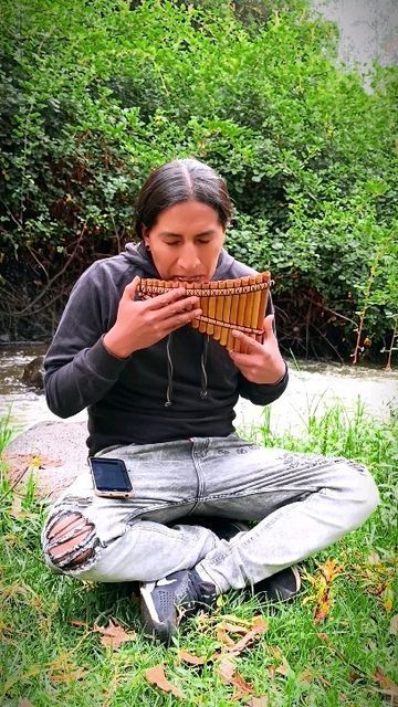 a woman sitting on the ground holding a basket in front of her face and looking at it