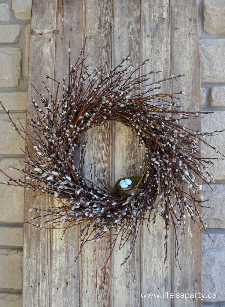 a wreath made out of twigs on top of a wooden door with a light blue glass in the center