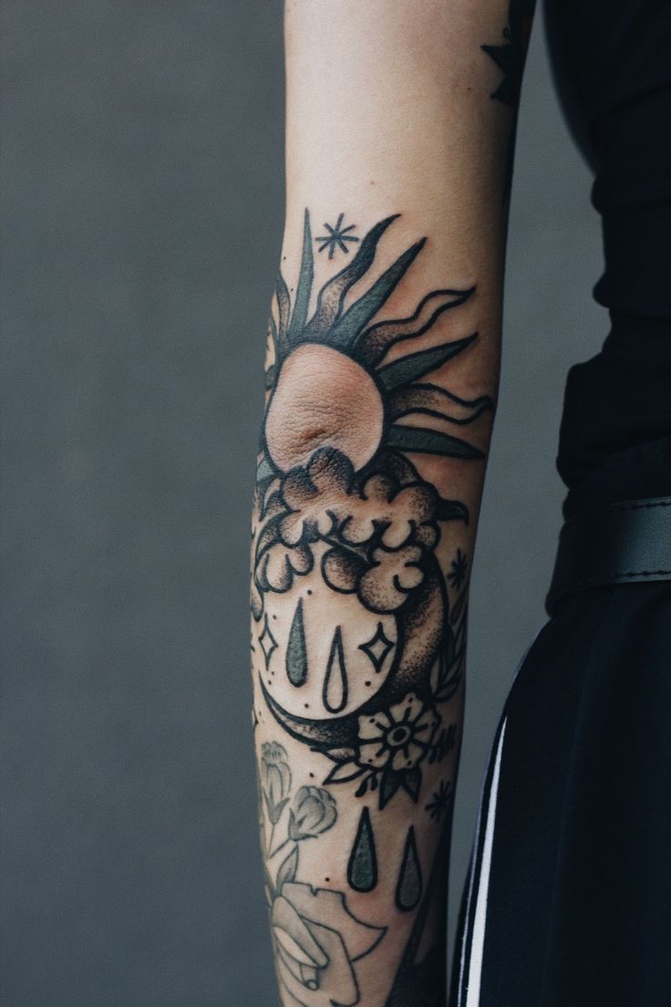 a person with a sun and rain tattoo on their arm