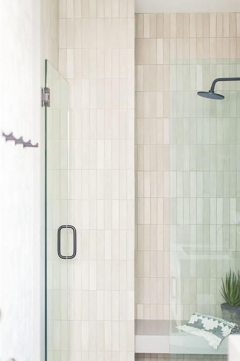 a bathroom with a glass shower door and tiled walls