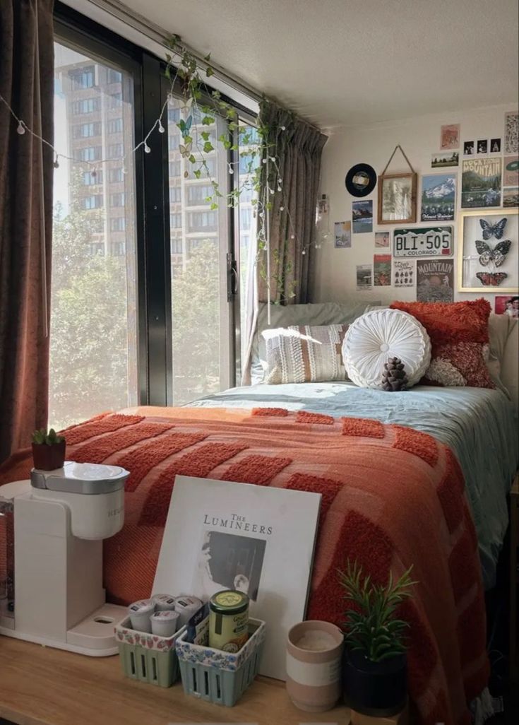 a bed room with a neatly made bed next to a large window and pictures on the wall