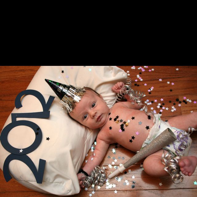 a baby laying on top of a pillow covered in confetti next to a birthday cake