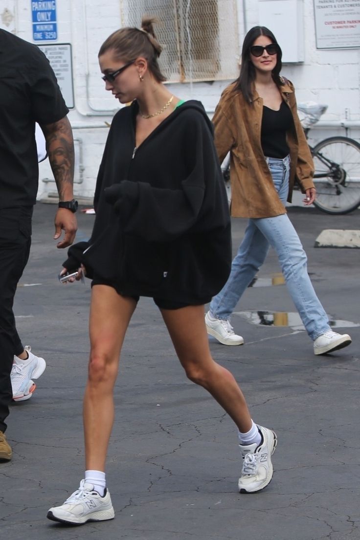 the woman is walking down the street with her foot in the air while wearing white sneakers