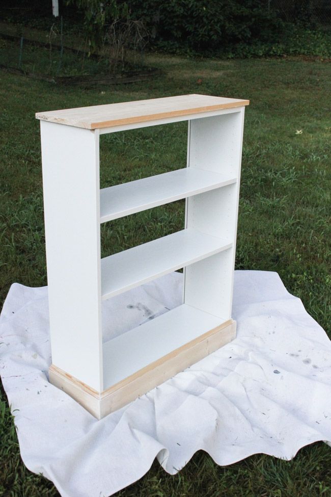 a white book shelf sitting on top of a blanket in the middle of a field