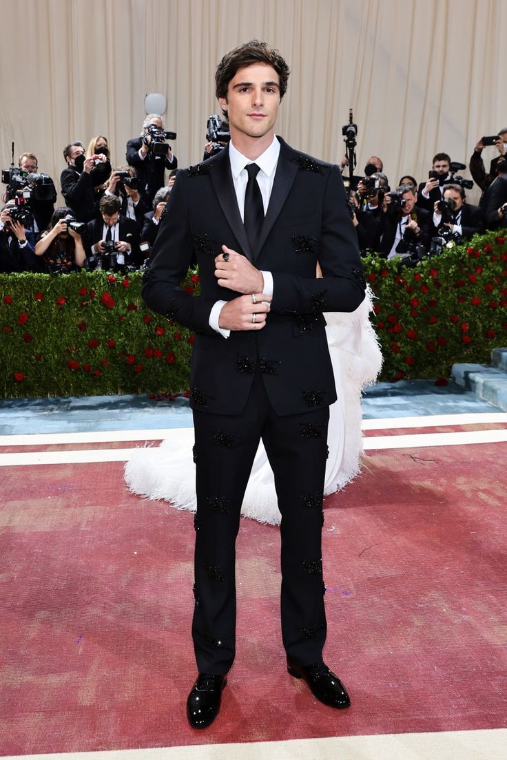 a man in a tuxedo standing on a red carpet