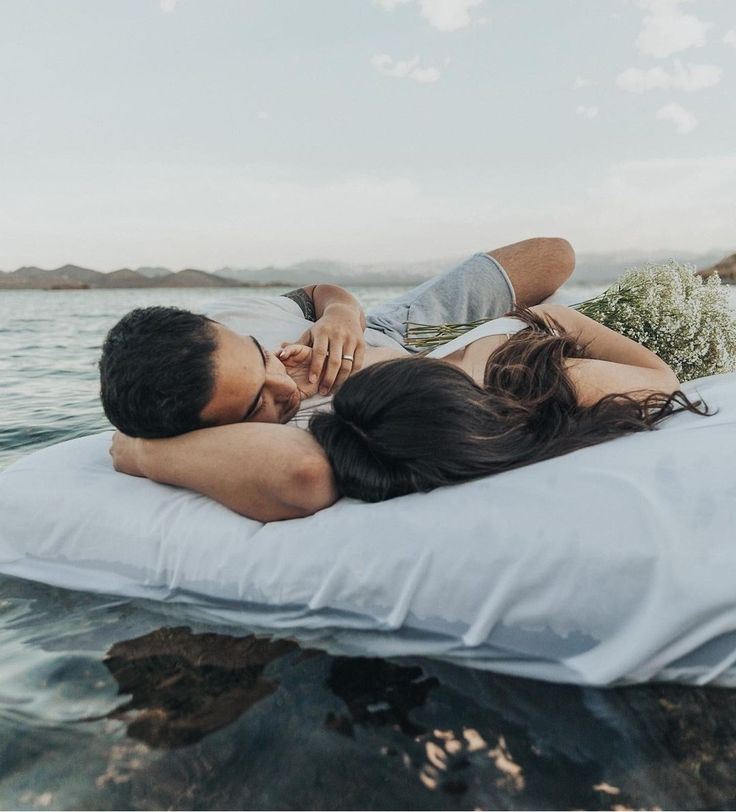 a man and woman laying on top of a mattress in the middle of the water