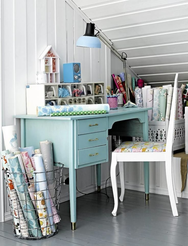 a desk and chair in a room with many items on top of it, including wrapping paper