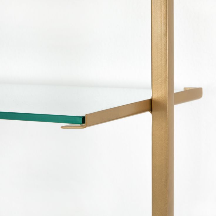 a close up of a metal shelf with green glass shelves on each side and gold brackets