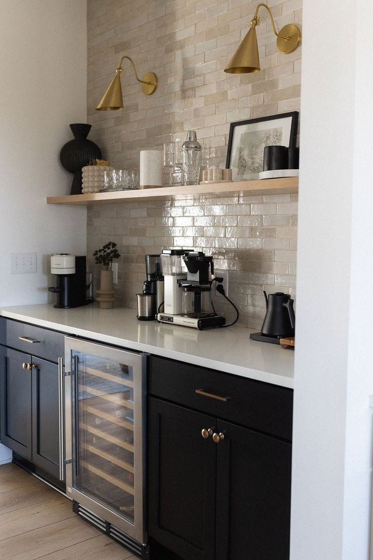 a kitchen with black cabinets and white counter tops, gold accents on the backsplash