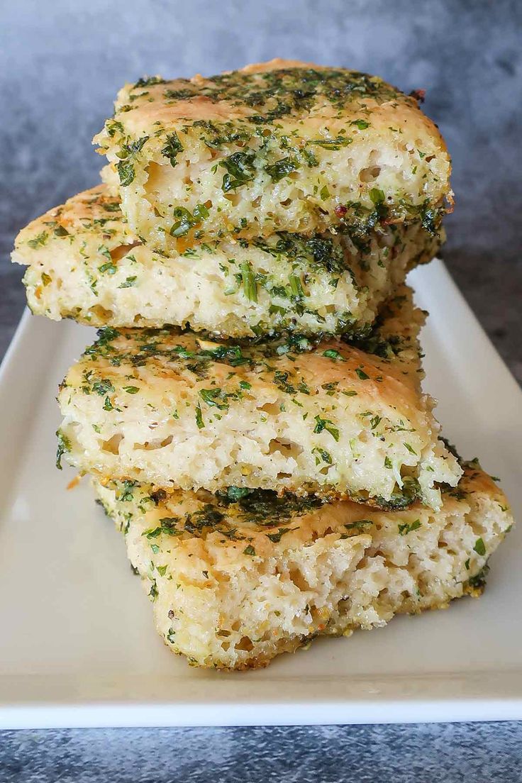 three pieces of broccoli and cheese scones on a white plate with a gray background