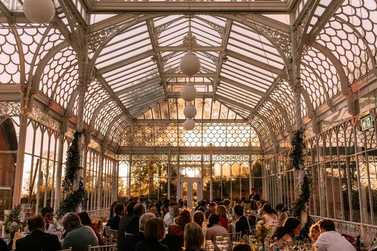 a group of people sitting at tables in a glass walled dining room with lots of windows