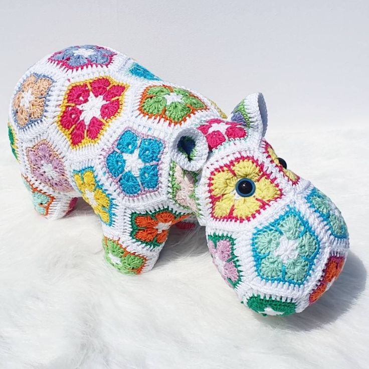 a crocheted hippo laying on top of a white furnishing covered floor