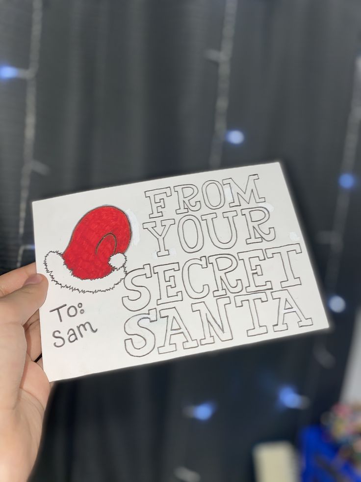 someone is holding up a card with santa's hat on it that says, from your secret santa