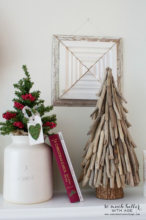 a small christmas tree sitting on top of a mantle next to a book and candle