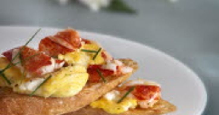 two pieces of bread topped with bacon and eggs on a white plate next to flowers