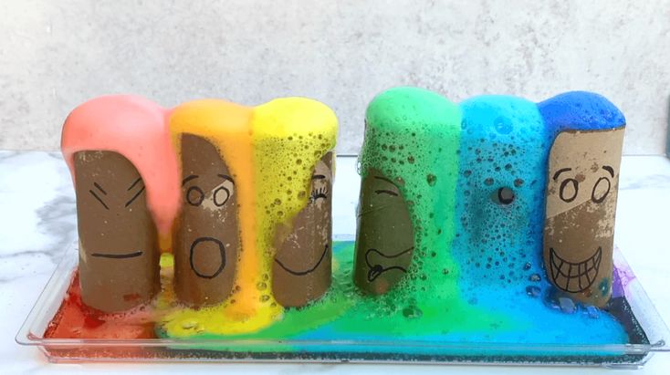 four different colored candles with faces drawn on them