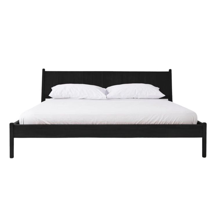 a bed with white pillows and black frame