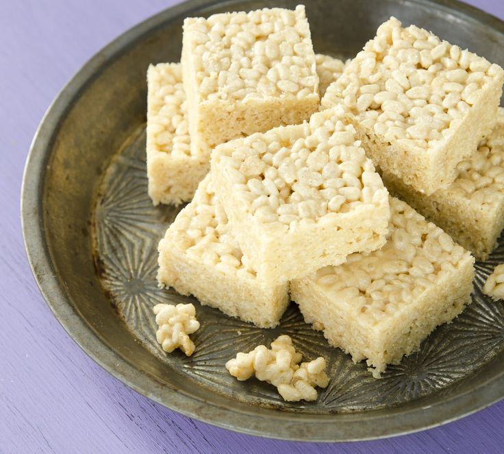 several pieces of rice krispy treats on a metal plate with purple table cloth behind it