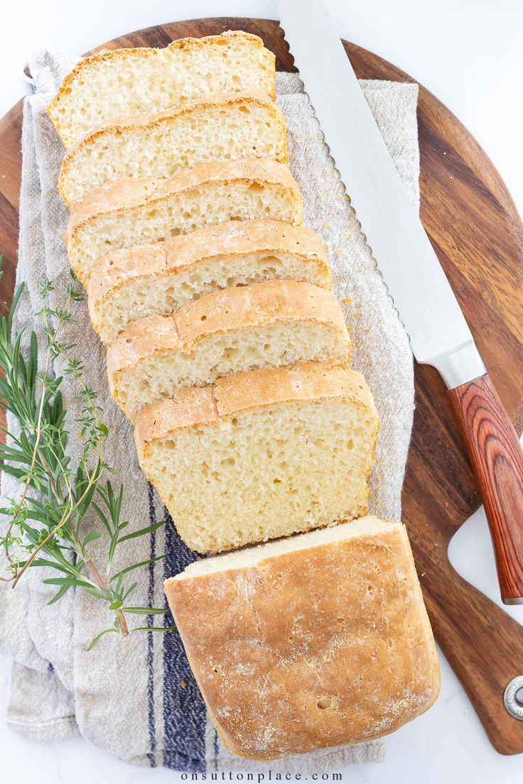 sliced loaf of bread sitting on top of a wooden cutting board next to a knife