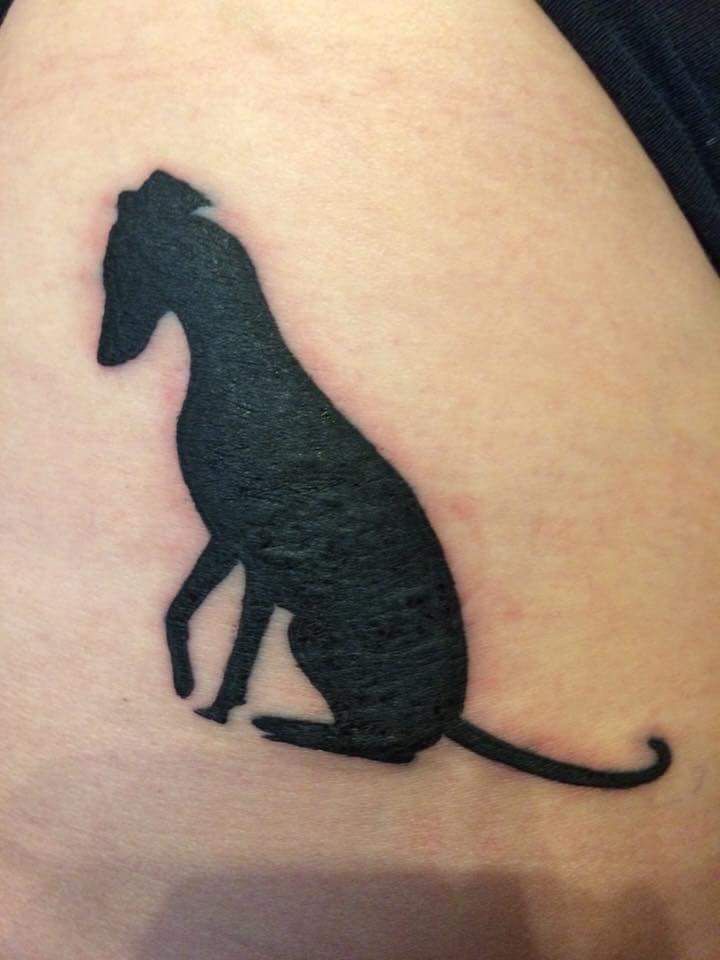 a small black dog tattoo on the side of a woman's thigh