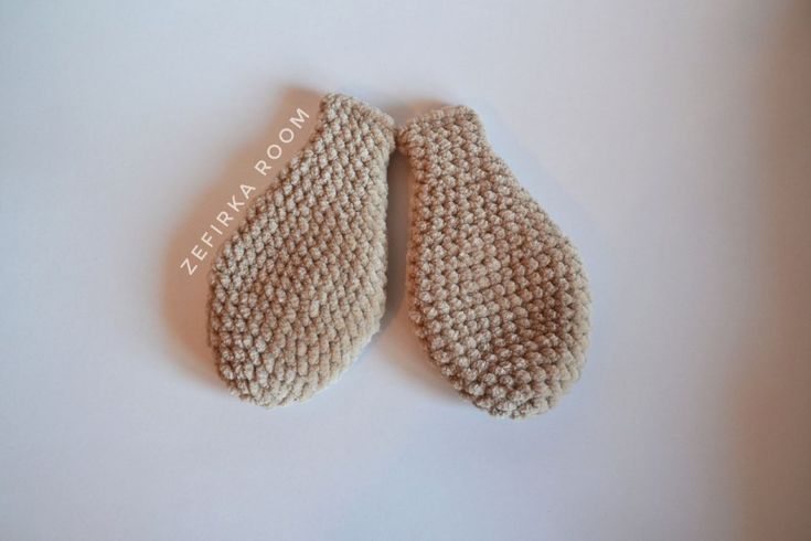 two knitted mittens sitting on top of a white table