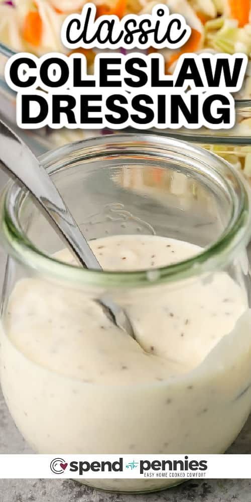 a glass jar filled with dressing sitting on top of a table next to a bowl of salad