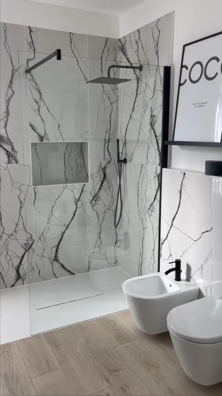 two white bowls sit in front of a marble shower wall with black and white accents