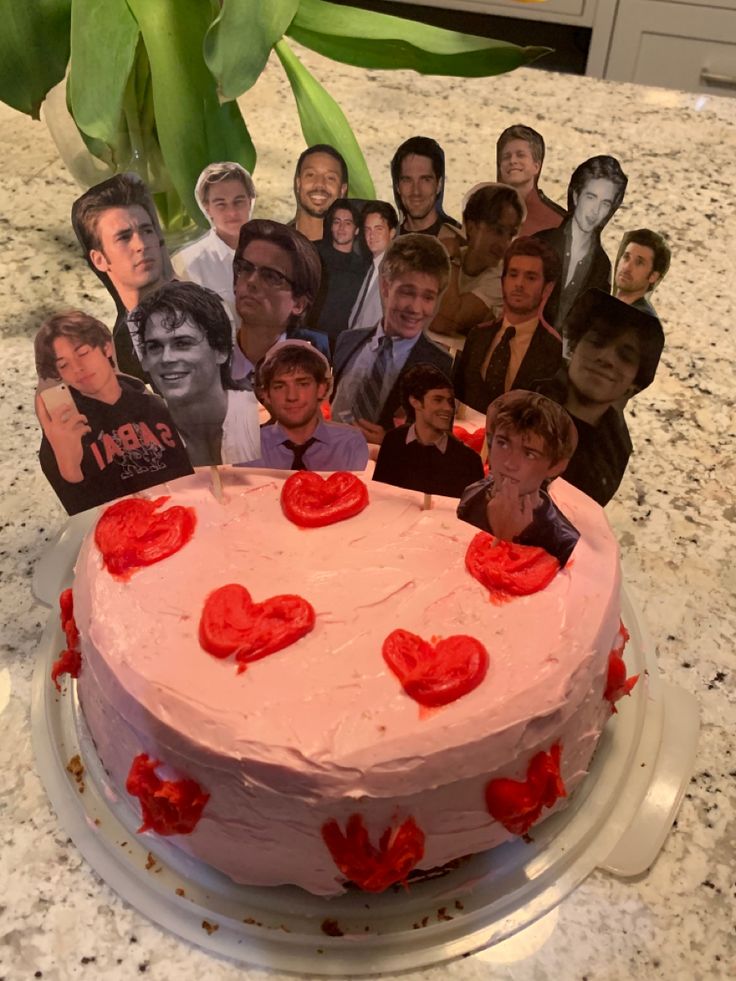 a birthday cake with many pictures of people and hearts on the frosting is displayed in front of a marble countertop