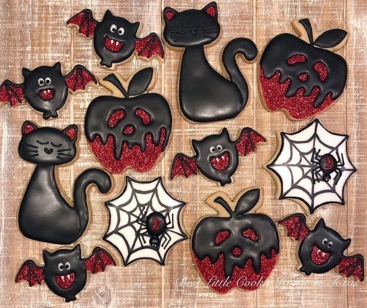 decorated cookies with black and red icing in the shape of cats, bats, and pumpkins