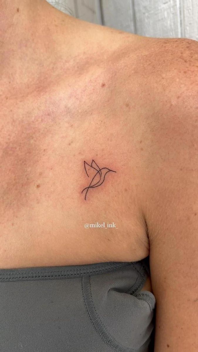 the back of a woman's shoulder with a small bird tattoo on her chest