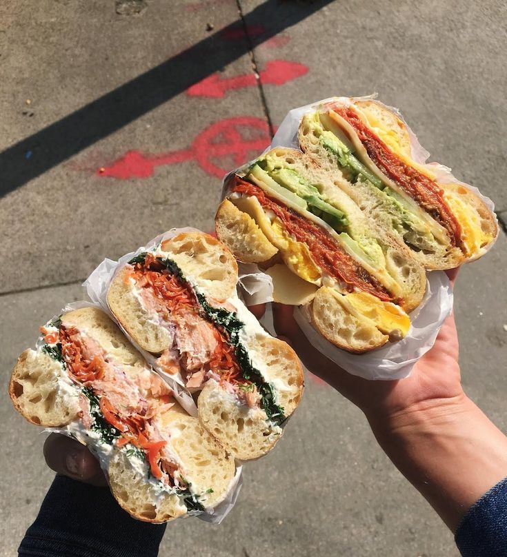 two sandwiches are being held in their hands