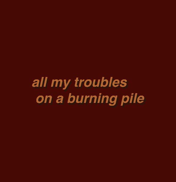 the words all my troubles on a burning pile are in brown and black font, against a dark red background