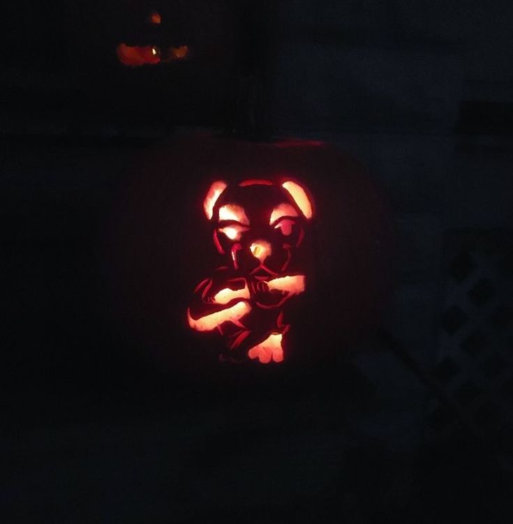 a pumpkin carved to look like a bear with its paw on it's chest