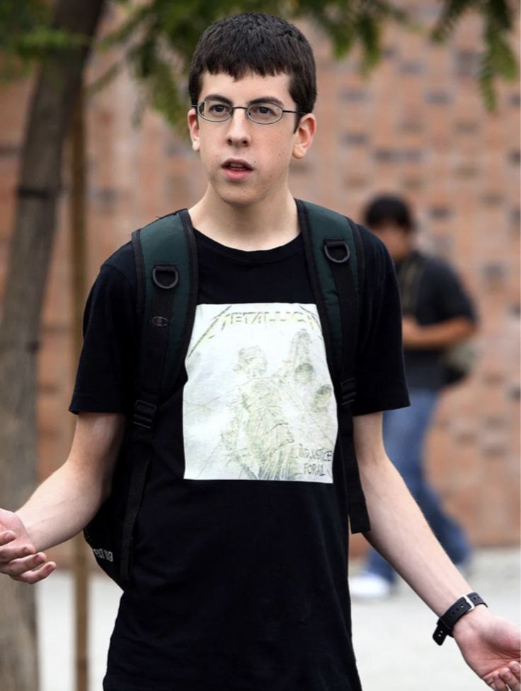 a young man with glasses holding his hands out