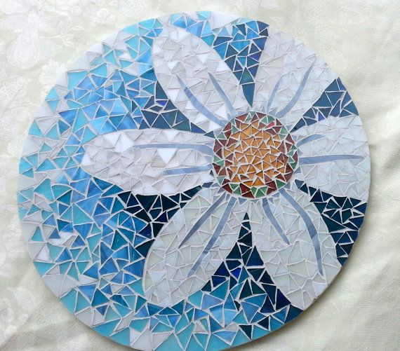 a flower made out of broken glass on a white tablecloth with blue and yellow mosaics