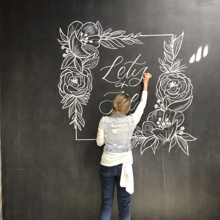 a woman writing on a blackboard with flowers