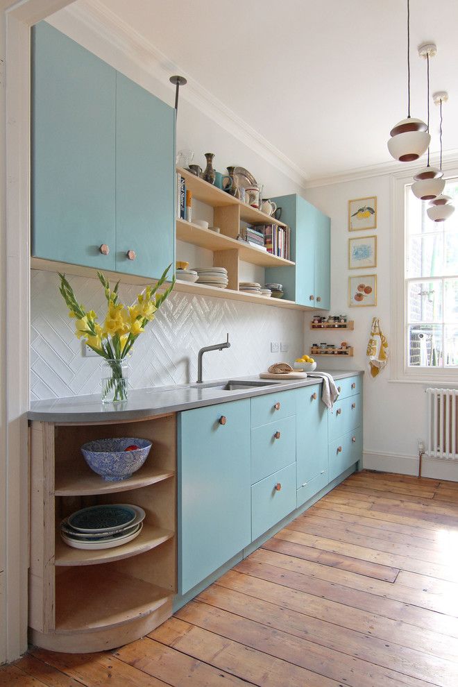 a kitchen with blue cabinets and wooden floors is pictured in this image, there are plates on the counter