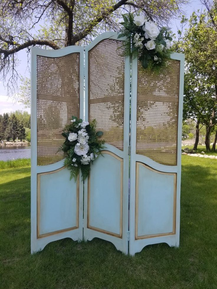 an old screen is decorated with flowers and greenery for a wedding or special event