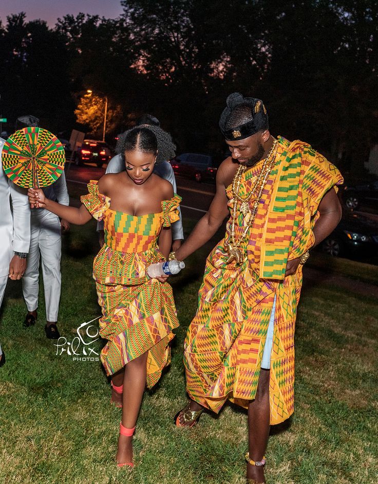 two people dressed in traditional african clothing holding hands