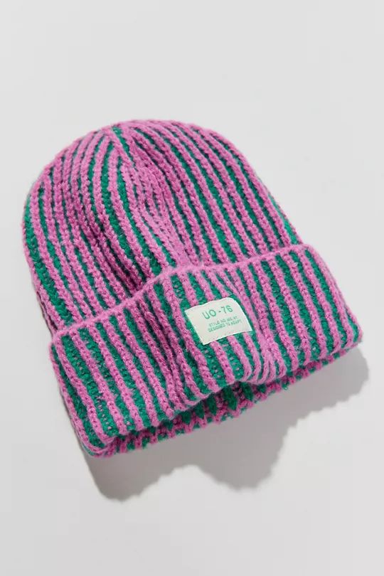 a pink and green striped beanie on a white background with a tag in the center