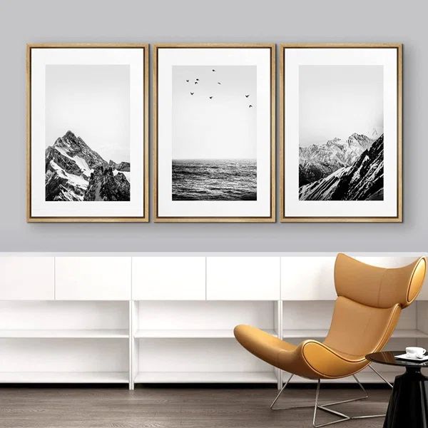 three black and white pictures hanging on the wall above a chair in a living room