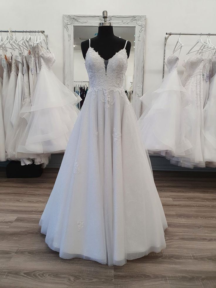 a white wedding dress on display in front of a mirror