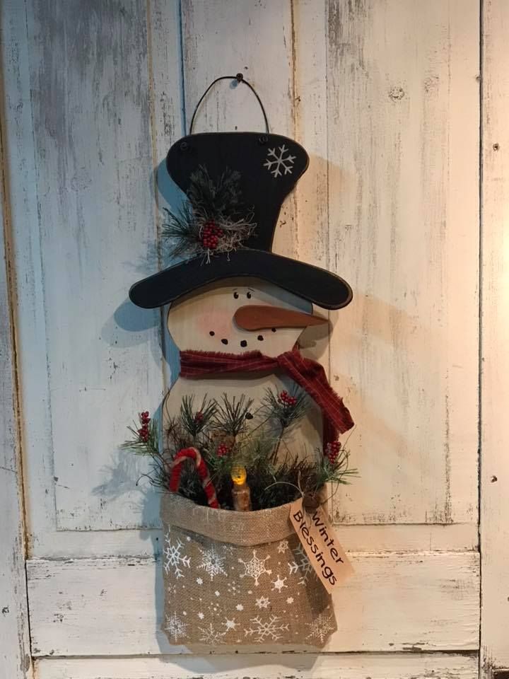 a snowman decoration hanging from the side of a white wooden door with christmas decorations on it