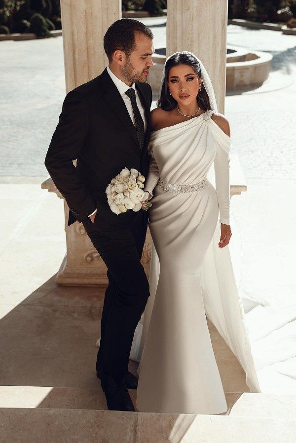 a bride and groom posing for a photo in front of some pillars with columns behind them