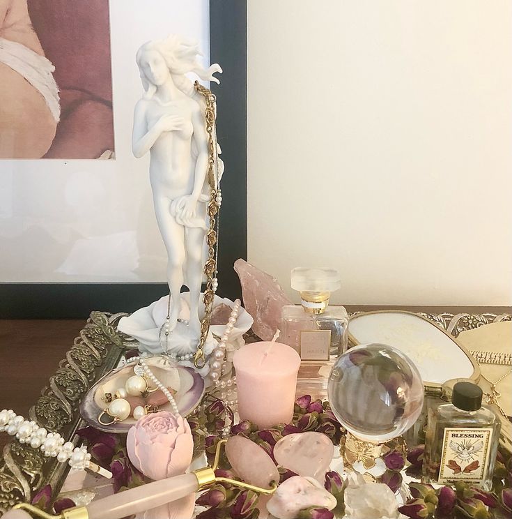 a table topped with lots of candles and other items next to a framed photo on the wall